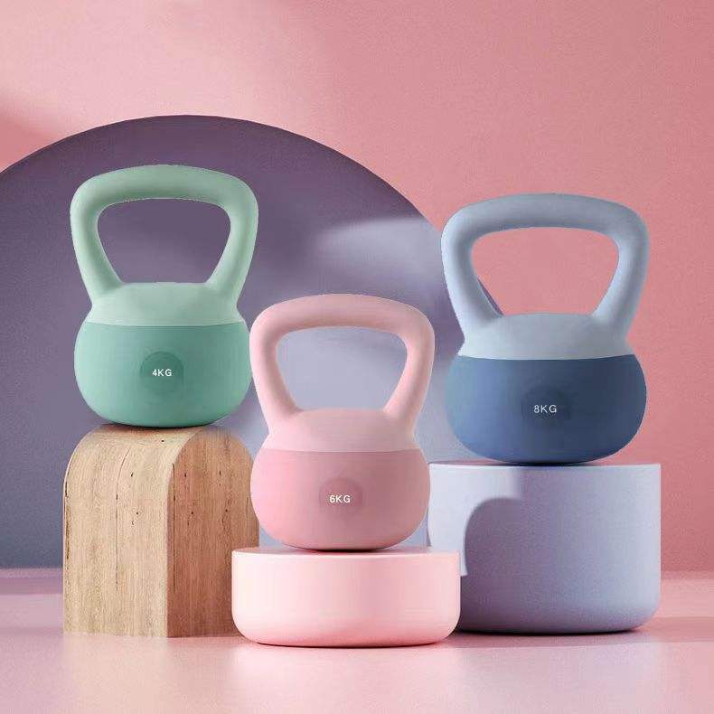 Three colorful kettlebells on stands against a pink and purple gradient background